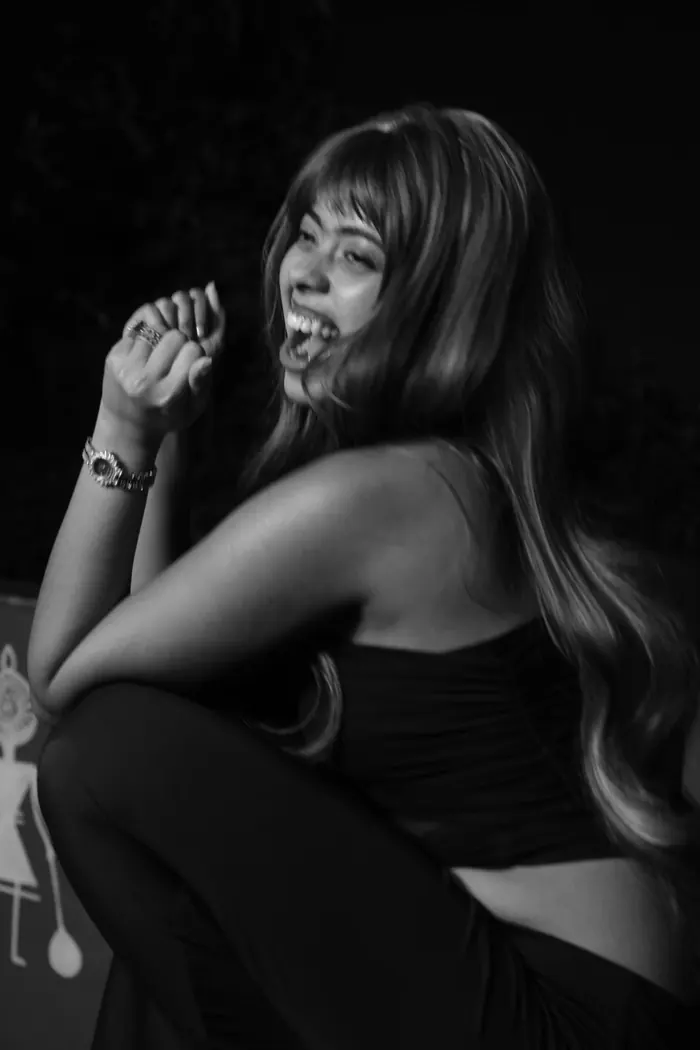 Black-and-white portrait of Sandipta laughing on a rooftop at night